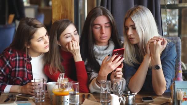Четверо друзей смотрят в телефон и смеются — стоковое видео