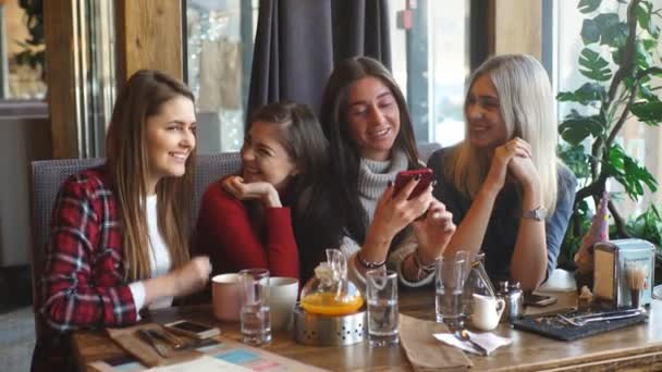 Concepto de comunicación y amistad - mujeres jóvenes sonrientes con tazas de café en la cafetería — Vídeos de Stock