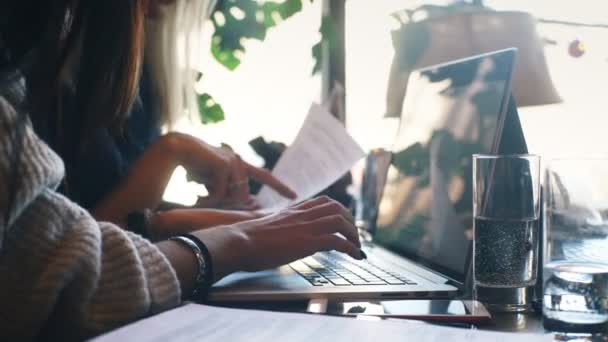Joven mujer de negocios escribiendo en el ordenador portátil en la cafetería — Vídeos de Stock