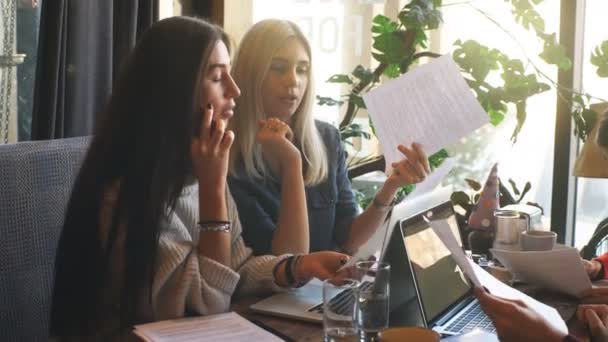 Vier junge Agenten sitzen im Café, diskutieren Papiere und organisieren die Arbeit — Stockvideo