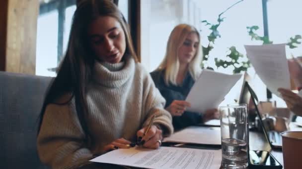 Молодая предпринимательница-фрилансер подписывает документы в кафе — стоковое видео