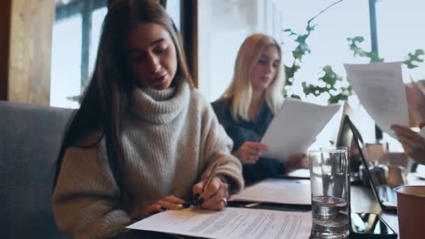 Joven empresaria freelancer firma documentos en cafetería — Vídeos de Stock