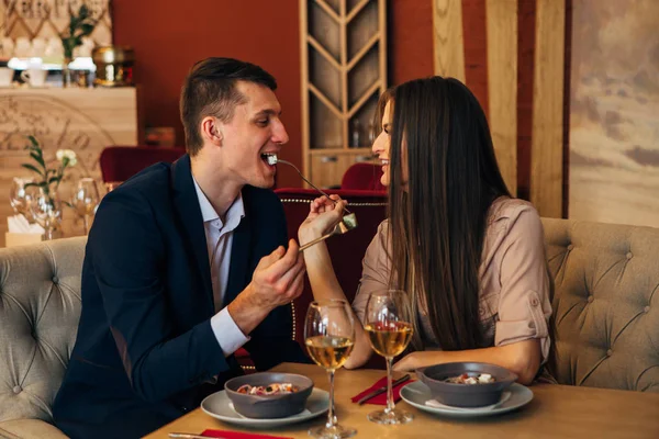 young couple feeding each other in restaurant