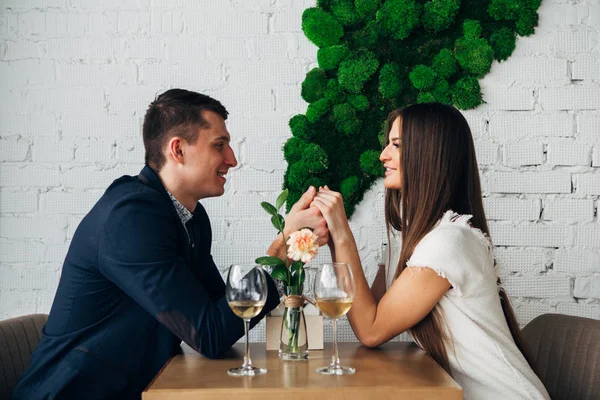 Улыбающаяся пара ужинает и пьет белое вино на свидании в ресторане — стоковое фото