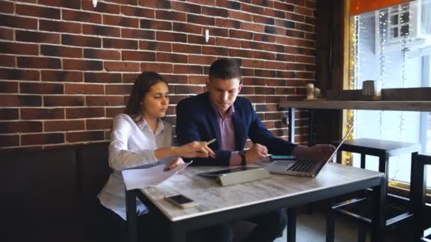 Doi tineri oameni de afaceri care lucrează pe laptop în cafenea — Videoclip de stoc