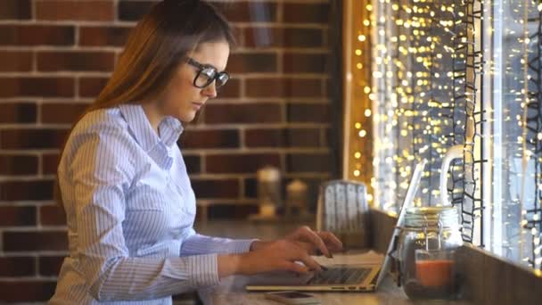 Nő dolgozik a laptop a kávézóban, és mosolyogva néz a kamerába. — Stock videók