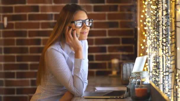 Bir kafede telefonda konuşurken neşeli genç iş kadını — Stok video