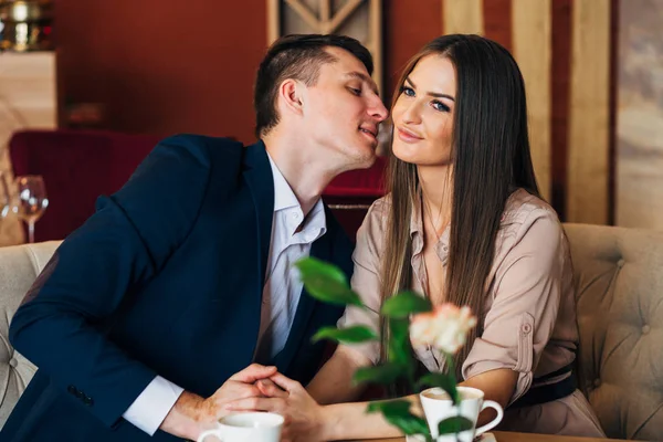 Een man kussen een vrouw in een restaurant tijdens het diner — Stockfoto