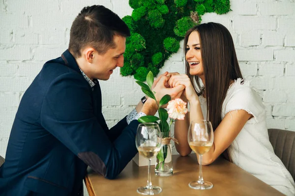 Glad ung man och kvinna är dating i restaurangen. De sitter vid bordet och tittar på varandra med kärlek. — Stockfoto