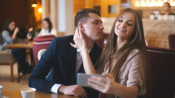 Casal amoroso alegre desfrutando de tecnologia moderna, se divertindo, capturando momentos brilhantes de férias no café — Vídeo de Stock