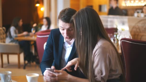 Embracing couple using mobile phone in cafe — Stock Video