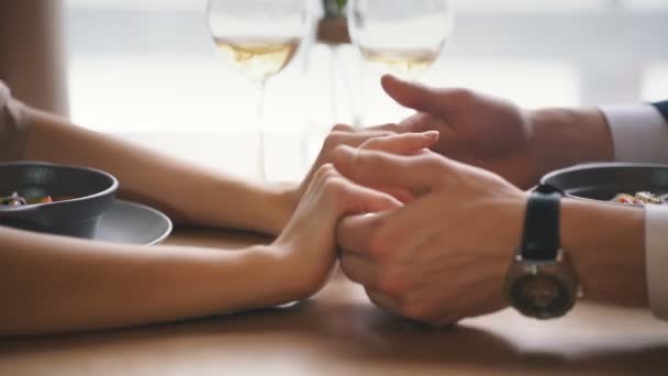 Primer plano de pareja joven cogida de la mano en la cafetería — Vídeos de Stock