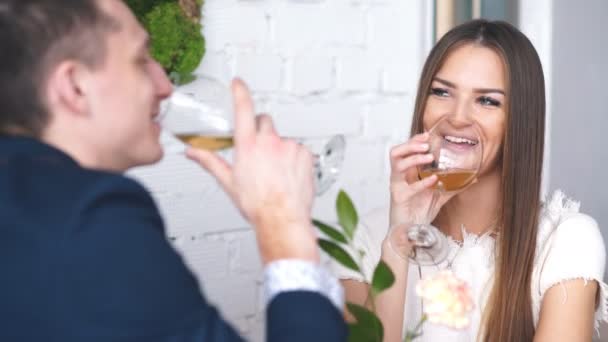 Vrolijke jonge man en vrouw dateren in restaurant. Ze zitten aan de tafel en kijken naar elkaar met liefde. — Stockvideo