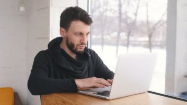 genç bir işadamı bir dizüstü bilgisayar ile bir kafede çalışıyor