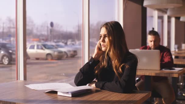 Молода бізнес-леді розмовляє по телефону в кафе — стокове відео