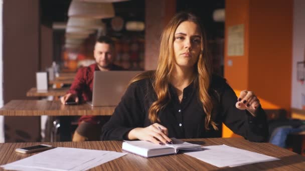 Cansada joven empresaria sentada a la mesa con un cuaderno — Vídeos de Stock