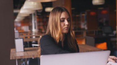 bir laptop ve alır notlar bir defter üzerinde siyah gömlekli ciddi iş kadını