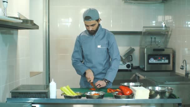Шеф-кухар у синьому фартусі нарізає перець — стокове відео