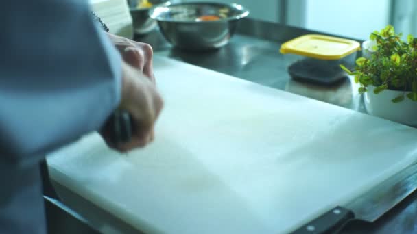 Шеф-повар режет лук на доске на кухне — стоковое видео