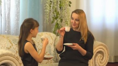 Anne ve kızı koltukta evde çay içme