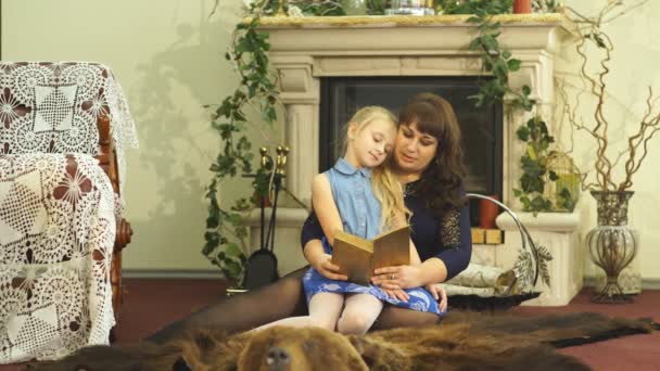Jovem mãe feliz com sua pequena filha sorridente lendo o bood juntos - dentro de casa — Vídeo de Stock