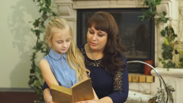 Mor med den älskade lilla dottern sitter på en stol och läser sagor — Stockvideo
