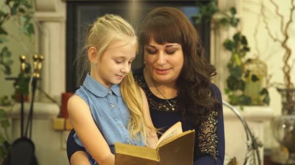Glad ung mamma med hennes lilla leende dotter läsa bood tillsammans - inomhus — Stockvideo