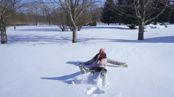 Un niño hace un ángel de nieve — Vídeos de Stock