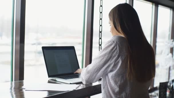 Giovane bella donna d'affari in camicia bianca che lavora su scrivania con computer portatile e documento in caffè . — Video Stock