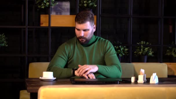 Hipster comprueba la hora de su reloj y bebe café — Vídeos de Stock