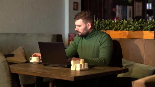 Pensive na volné noze pracuje na novém projektu v kavárně. Vážný obchodník s pozorným vzhledem pije kávu — Stock video