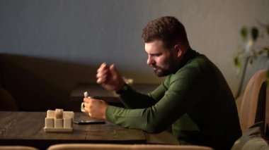Bir adam bir kafede kulağına kulaklık takar ve en sevdiği müziği dinler.
