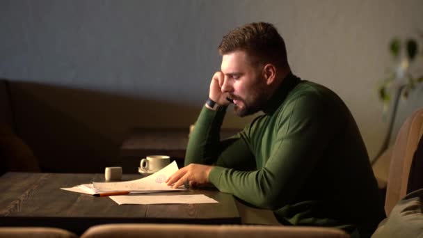 Un hombre de negocios está hablando por teléfono y discutiendo un contrato por teléfono en un café — Vídeo de stock