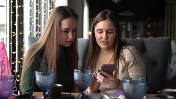 Flicka visar något sin vän på mobilen. — Stockvideo