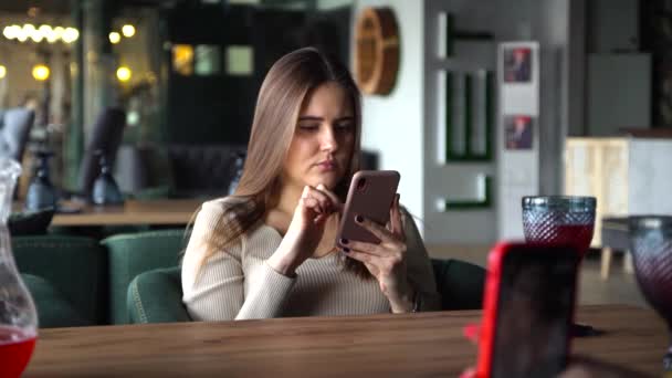 Mädchen sitzt im Coffeeshop und spielt im Urlaub Handy für soziale Medien — Stockvideo