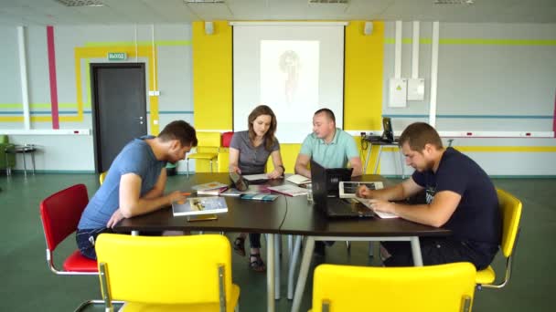 Uczniowie siedzą w bibliotece i przygotowują się do egzaminu — Wideo stockowe