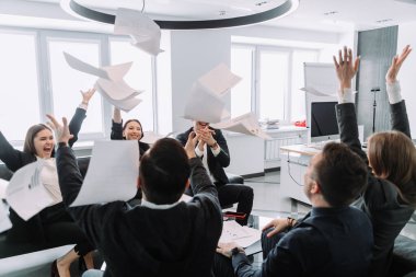 Mutluluktan havalara uçan çeşitli iş adamları kağıtları fırlatıp başarıyı kutluyor.
