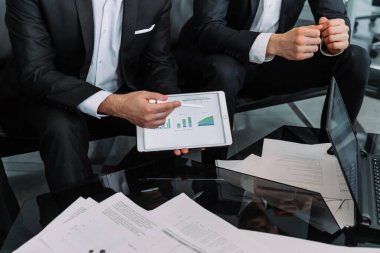 Yönetici, iş arkadaşlarına artan istatistikleri ve artan programları gösteren bir mali rapor sunar