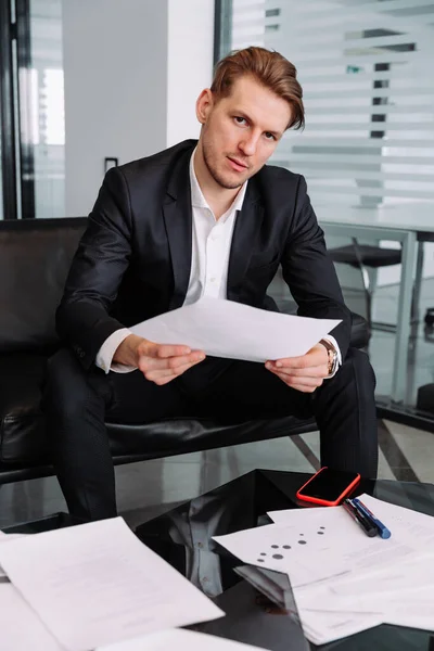 Hombre de negocios guapo sentado en el sofá en la oficina moderna Fotos De Stock