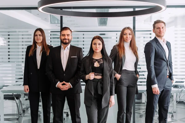 Sorrindo equipe de negócios em pé no escritório e olhando para a câmera Imagens De Bancos De Imagens