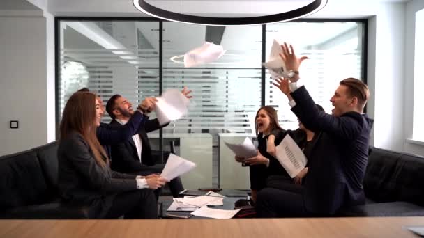 Grupo de empresários se alegrar em fechar o trimestre com sucesso jogando documentos em papel no escritório moderno, câmera lenta — Vídeo de Stock