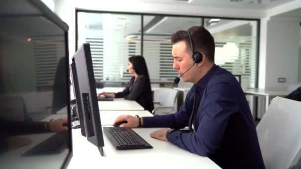 Handsome male customer service agent working in call center office as a telemarketer. — Stock Video