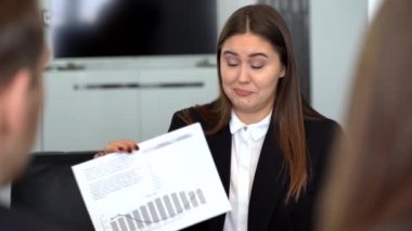 Yönetici, iş arkadaşlarına artan istatistikleri ve artan programları gösteren bir mali rapor sunar