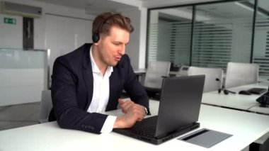 Ofiste otururken dizüstü bilgisayarla çalışan, yüzü kulaklarıyla gülümseyen Kafkasyalı serbest yazar.