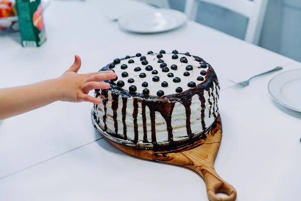 Första kakan.barnet tar kakan med handen. hand i konditorigrädde. barnens semester — Stockfoto