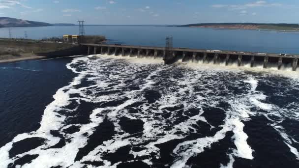 Vista aérea, feita por drone, de uma barragem de usina hidrelétrica. A força da água no vertedouro é observada . — Vídeo de Stock