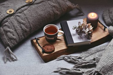 Sıcak bir çay, buhar, battaniye, kitap ve mumlarla dolu bir ev. Hygge ev içi.