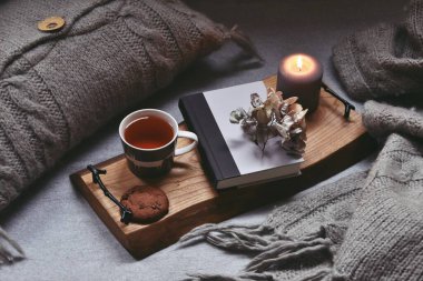 Bir fincan çay, ekose ve mumla rahat bir ev.  