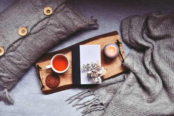 Bir fincan çay, ekose ve mumla rahat bir ev.  