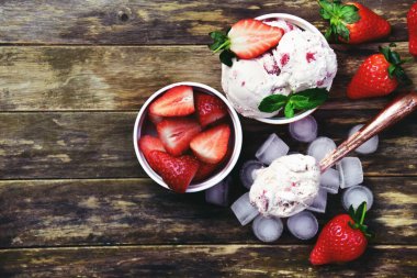 Ahşap arka planda iki kase çilekli dondurma. Boşluğu ve üst görünüm fotoğrafını kopyala